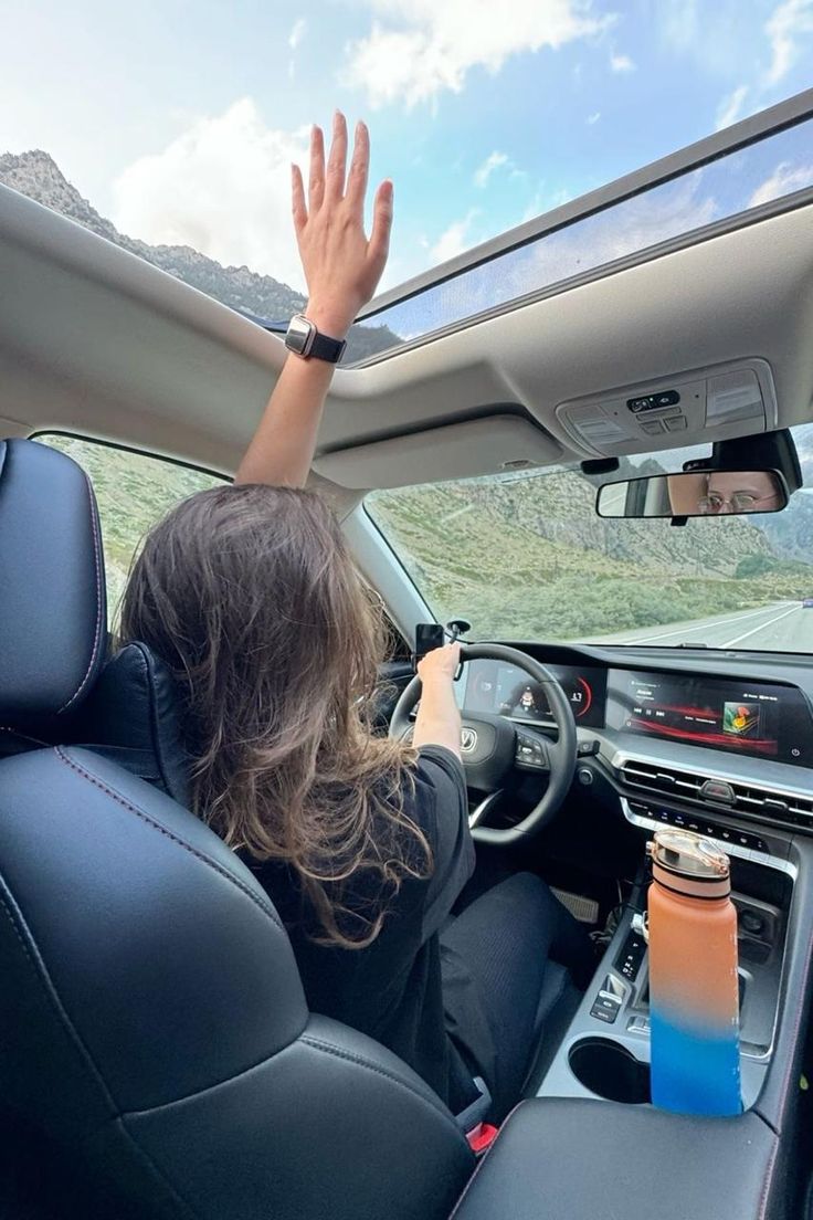 Driver with hand out of the sunroof on a mountain road